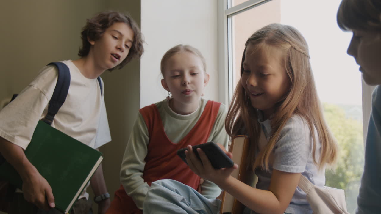 Group of diverse students interacting and looking at a smartphone during a school break