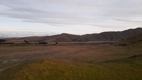 Aerial-establishing-shot-of-a-dry-and-brown-alpine-plateau-in-the-mountains-of-Canterbury,-New-Zealand