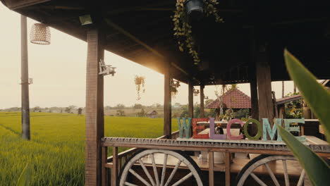 wooden porch with welcome sign overlooking rice paddy fields at sunrise/sunset