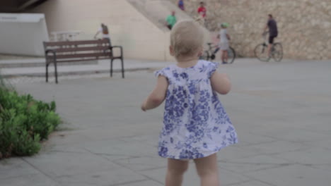 Back-view-of-baby-girl-walking-in-the-street