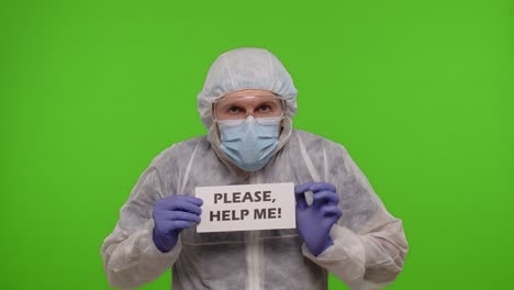 man in medical suit holding 'please, help me' sign on green screen