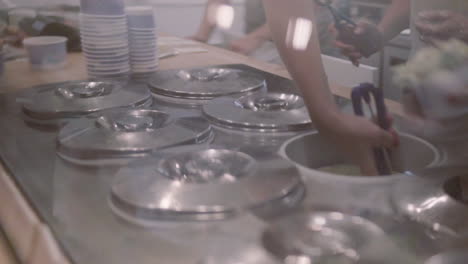 View-of-the-counter-in-the-ice-cream-parlour,-the-seller-puts-ice-cream-from-the-container,-summer-refreshment-with-ice-cream