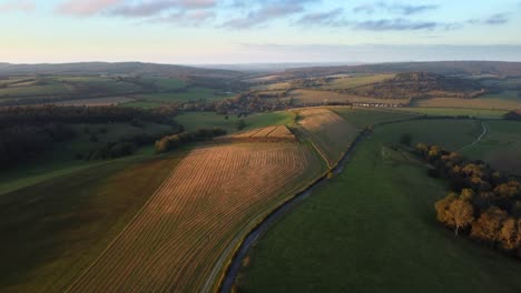 Aerial-tilt-up-shot-as-the-sun-sets-over-the-pristine-scenery-of-the-South-Downs-Way,-England