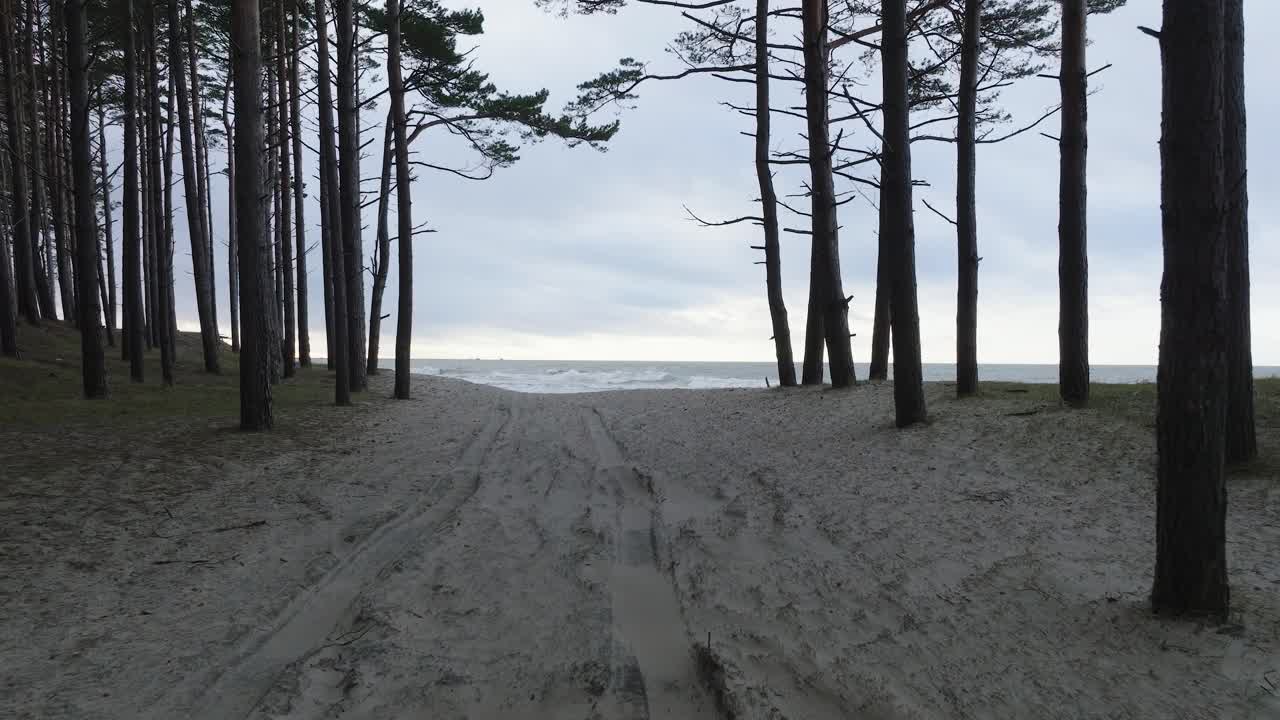 vista aérea de las grandes olas tormentosas rompiendo contra la playa de arena blanca, día nublado, dunas costeras dañadas por las olas, erosión costera, cambios climáticos, amplio tiro bajo de drones avanzando