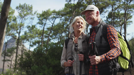 una pareja de ancianos activos sonriendo en el bosque.