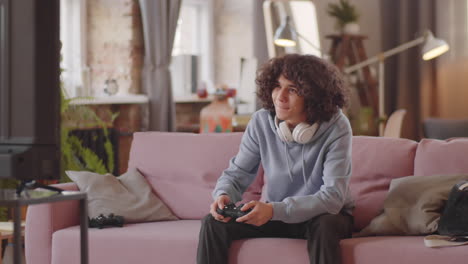 un adolescente alegre jugando a un juego de consola en casa