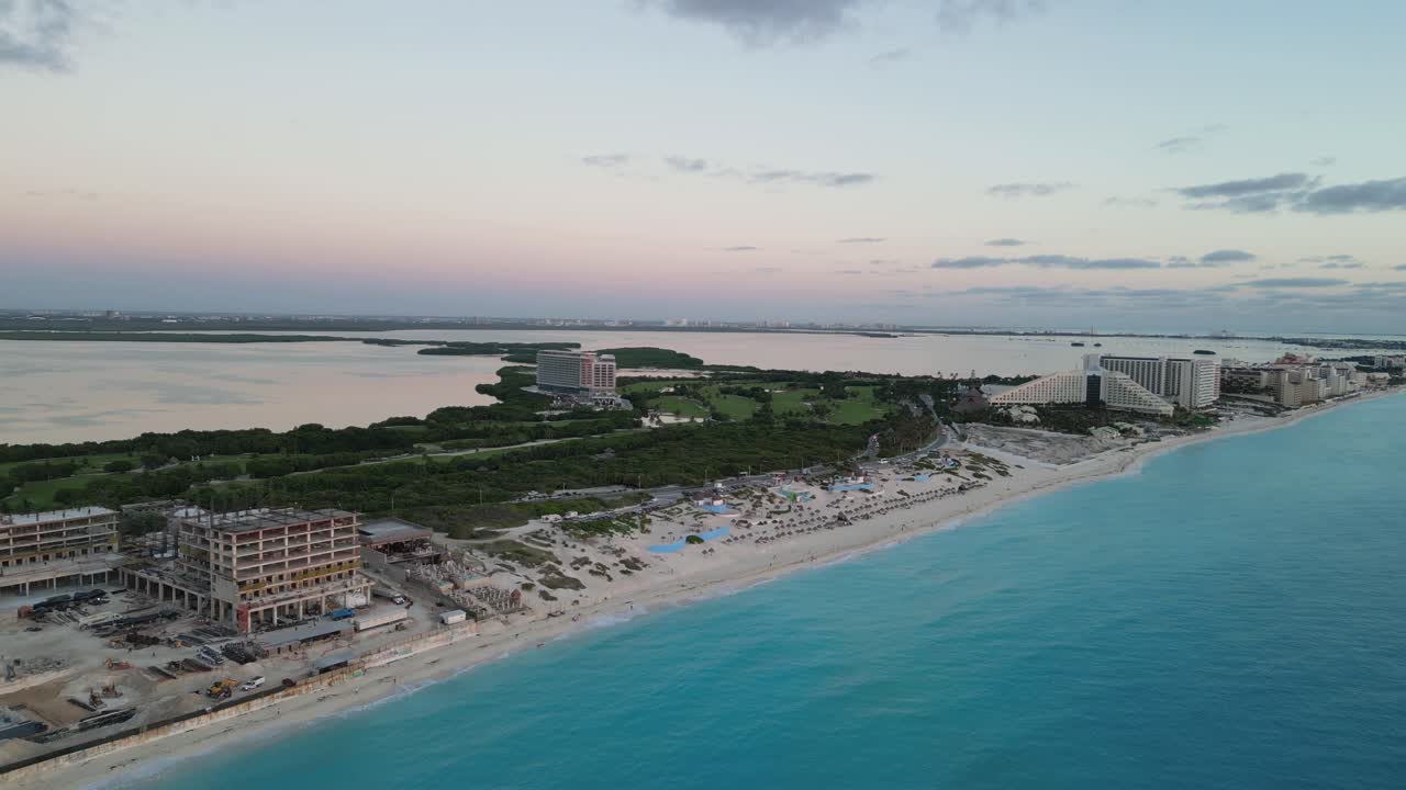 Sunset view of Cancun coastline with clear blue water, hotels, and construction site, playa delfines
