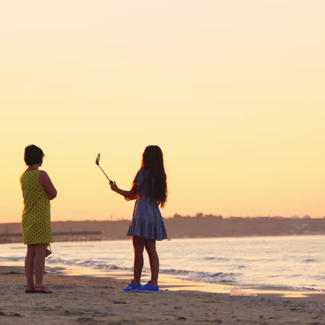 pretty girl in sunglasses taking photo of herself on the sea background. evening landscape on the sea shore and women standing at sunset.