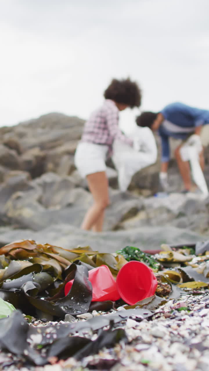 una pareja biracial disfruta de un momento lúdico en una playa rocosa.
