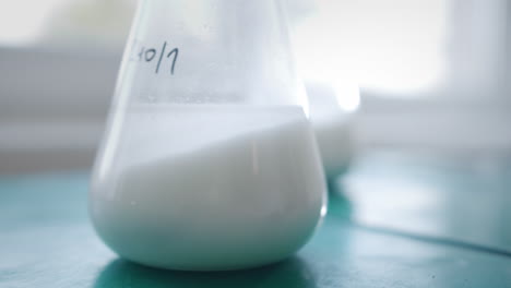 test tubes filled with white liquid are being shaken in a chemistry laboratory, representing the effort to find cures for cancer and covid-19