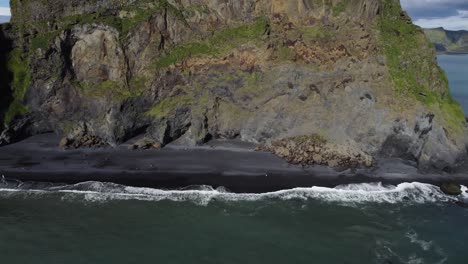 Luftaufnahme-über-Dem-Strand-Von-Reynisfjara-Mit-Nach-Oben-Geneigter-Aufnahme,-Um-Die-Klippenlandschaft-Freizugeben