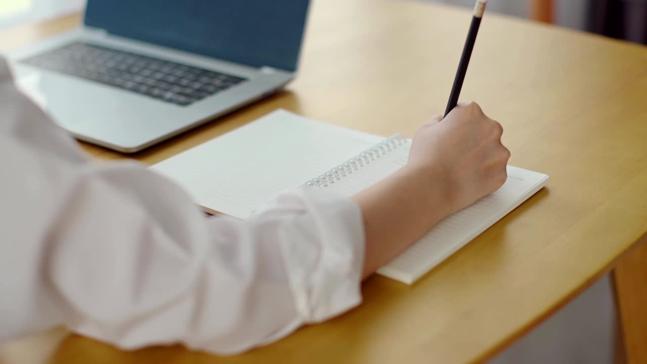 la mano de la mujer usa el lápiz para escribir en el cuaderno