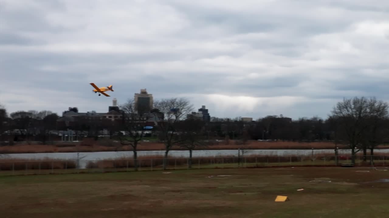 구름이 많은 날 호수와 함께 공원에서 날아다니는 노란색 원격 제어 비행기