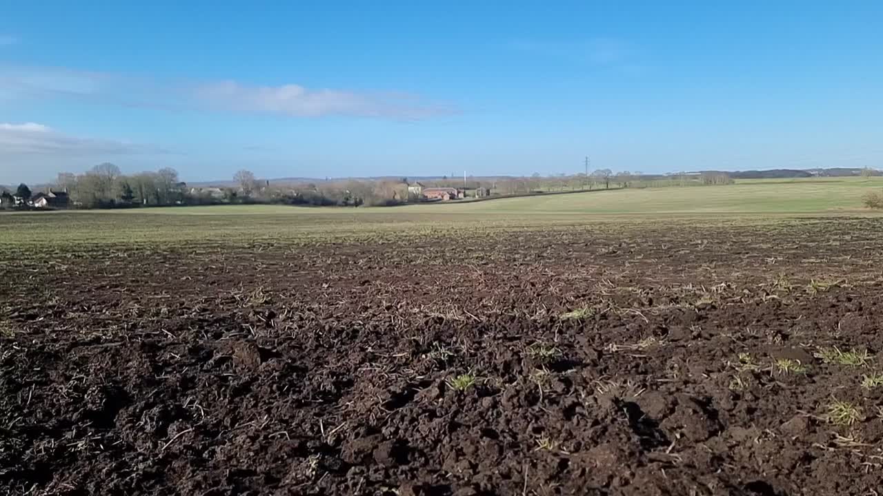 Suelo de cultivo seco recién arado bajo un cielo azul soleado por la mañana, preparado para la siembra estacional