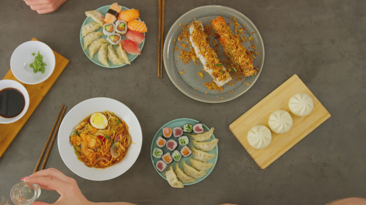 vista aérea de amigos en un restaurante chino haciendo tostadas con vino de arroz antes de compartir la comida