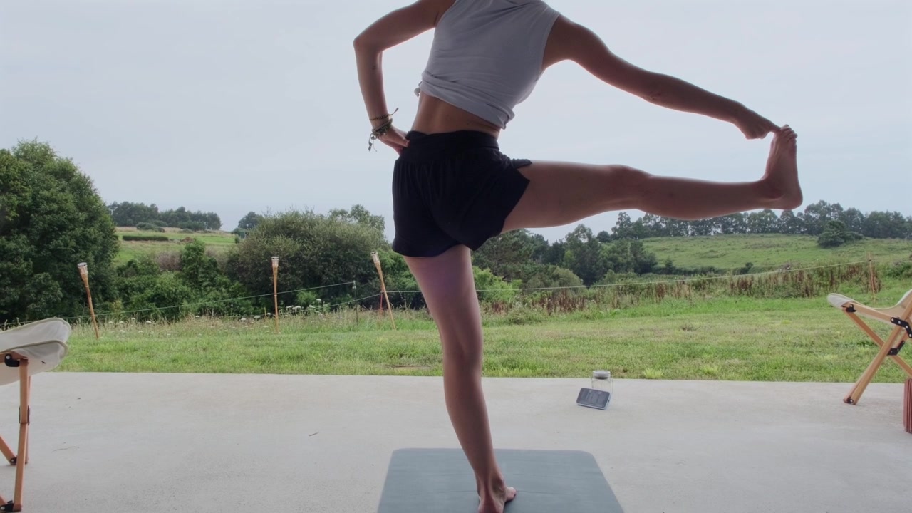 Woman balancing on one leg during yoga session outdoors