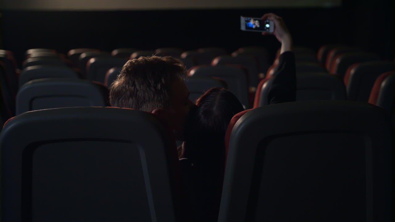 jóvenes besándose en una sala de cine vacía. una pareja de amor haciendo una foto selfie
