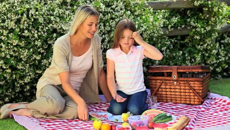 Young-woman-and-daughter-having-a-picnic-on-lawn