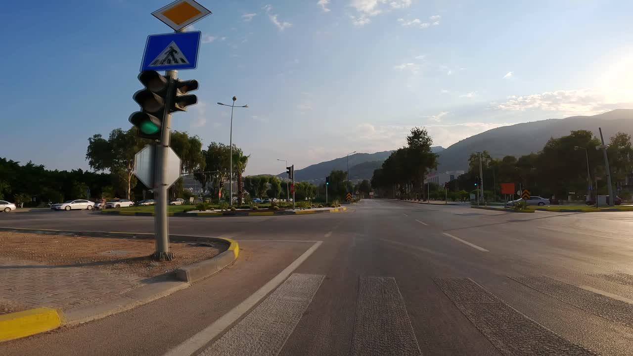 una vista desde un vehículo de una intersección, con los semáforos cambiando de rojo a amarillo y luego a verde