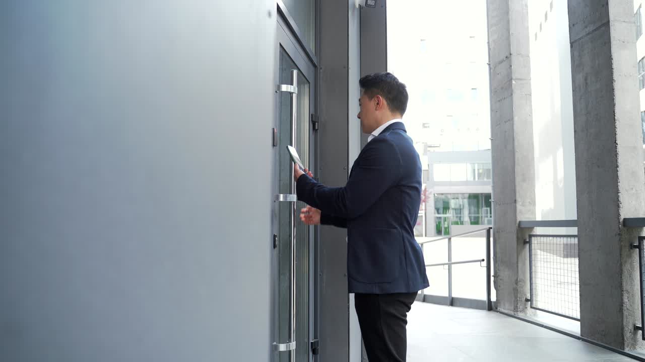 male asian businessman unlocking door using mobile phone application.