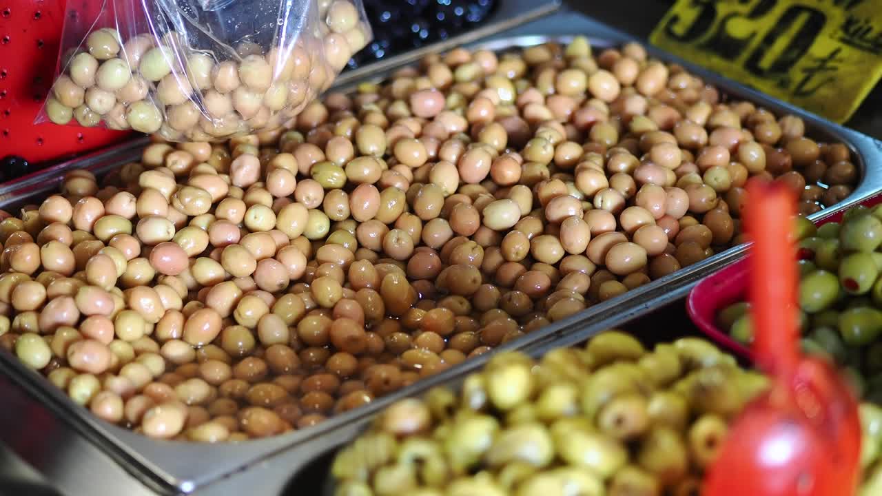 Mano che raccoglie olive verdi fresche da una bancarella del mercato