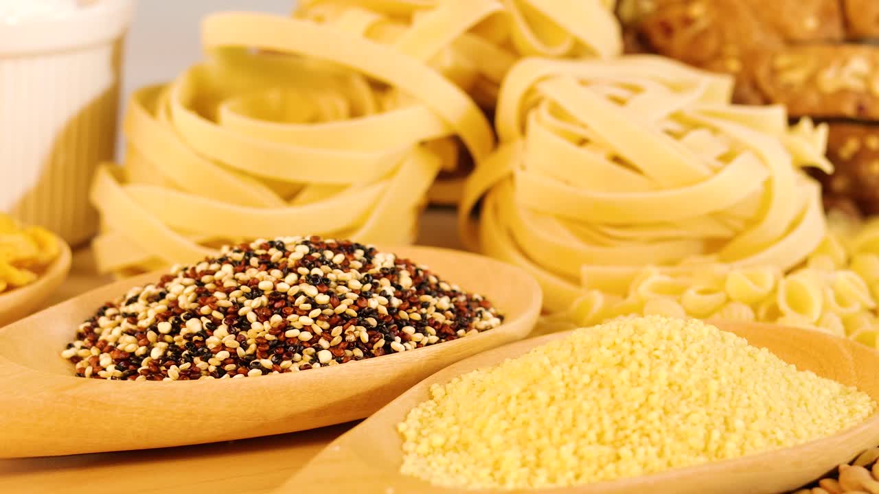 A variety of grains and pasta arranged with warm lighting, showcasing texture and color in a static composition