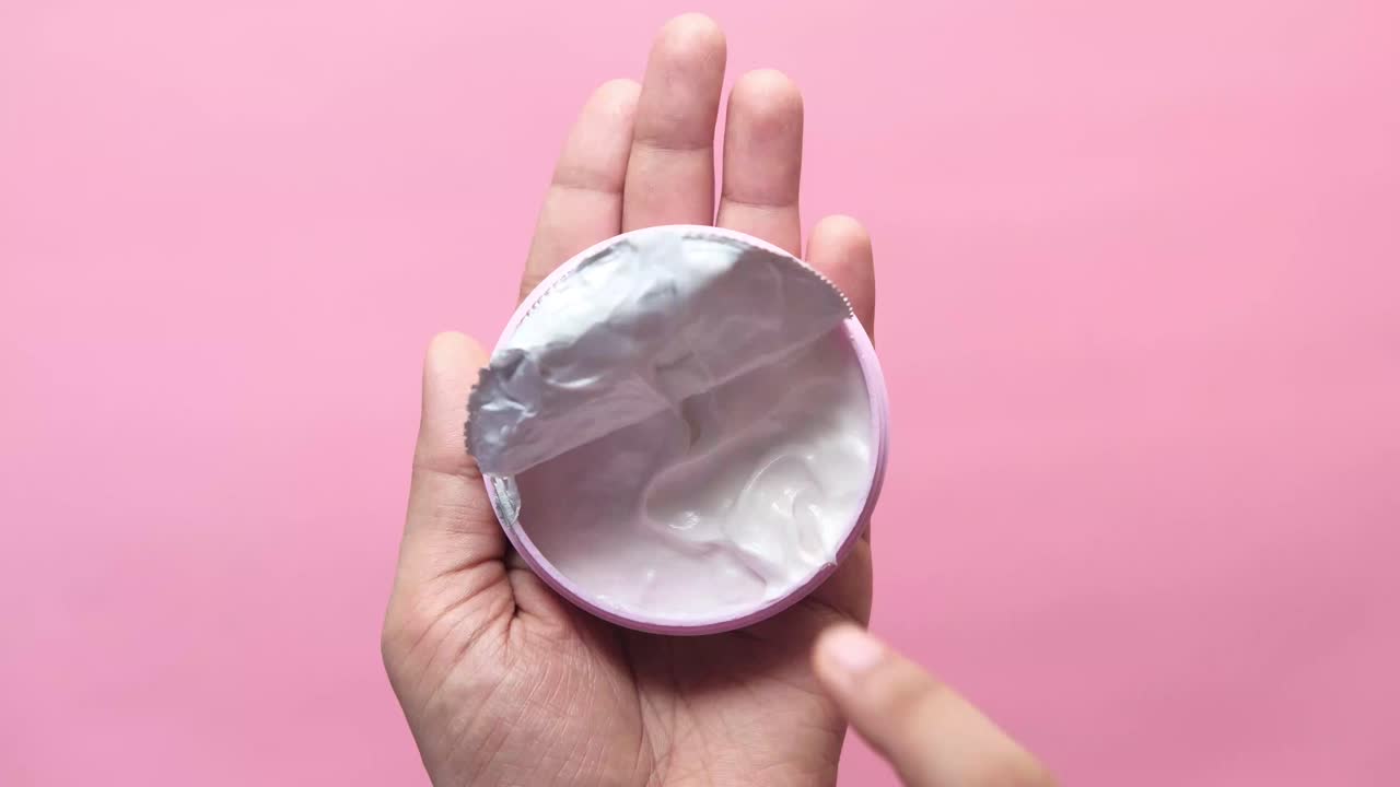 mano con un frasco abierto de crema