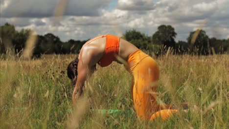 woman doing yoga cat cow pose in long grass field. day time sunny uk, hertfordshire medium shot