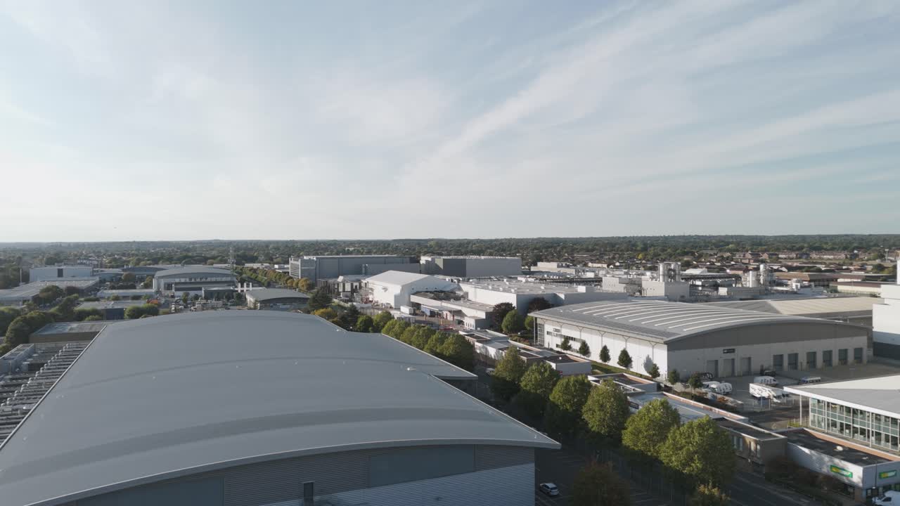 Low sweeping aerial perspective of Slough trading estate's industrial landscape in golden light, Berkshire, UK, October 2024