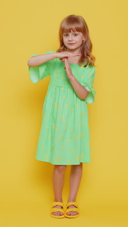 tired serious upset blonde child girl in dress showing pause gesture limit or stop sign time out