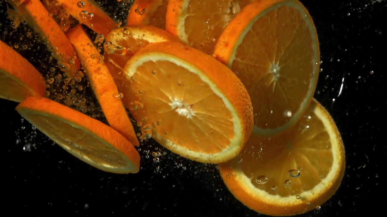 Fette d'arancia fresche che cadono e schizzano nell'acqua