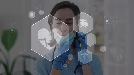 animation of medical icons over caucasian female doctor wearing face mask in hospital