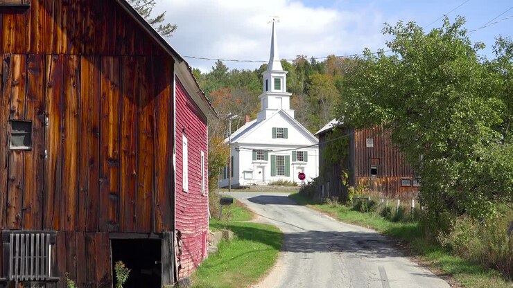 Un'incantevole scena di un piccolo villaggio nel Vermont con chiesa, strada e fattoria.