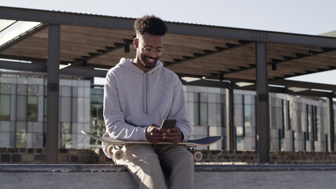Man using phone while sitting on skateboard in urban park