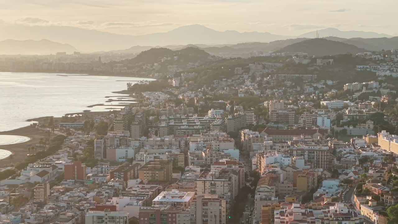Una vista aerea cattura il tramonto durante l'ora d'oro sulla costa di Malaga e sul centro storico della città. Mette in evidenza il turismo nel Mediterraneo, la bellezza costiera e lo stile di vita urbano.