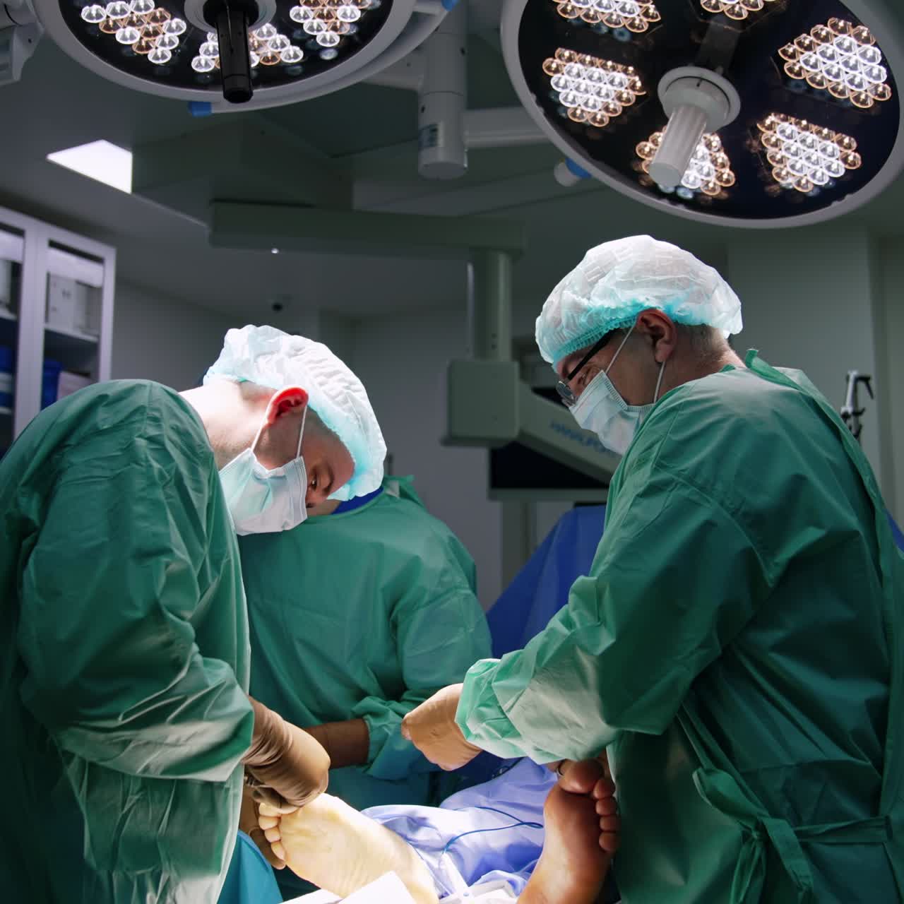 Chirurghi collaboratori operano un piede ferito. L'assistente passa gli strumenti di metallo ai dottori.