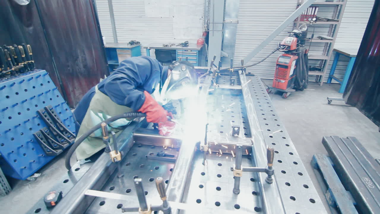 防護服とマスクを着用した作業員が金属溶接を行う。工場溶接工。