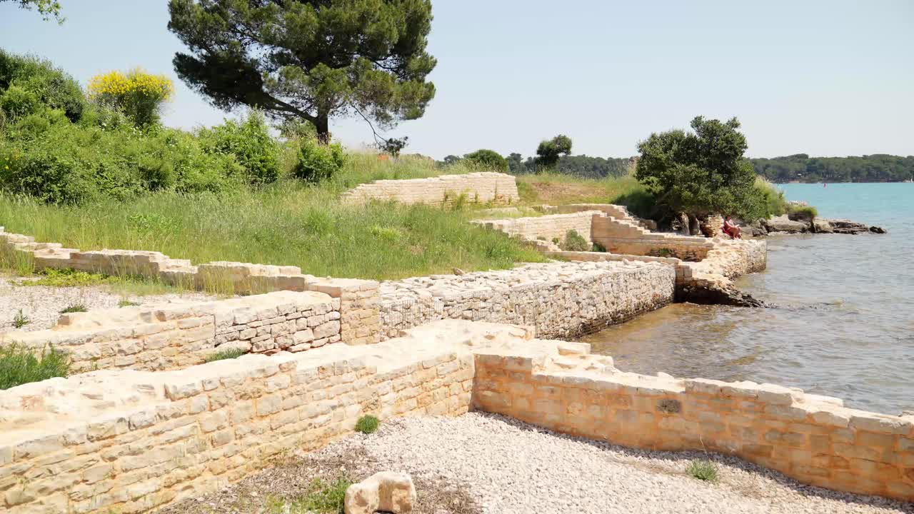 Le fondamenta di una villa romana accanto all'acqua calma del mare.