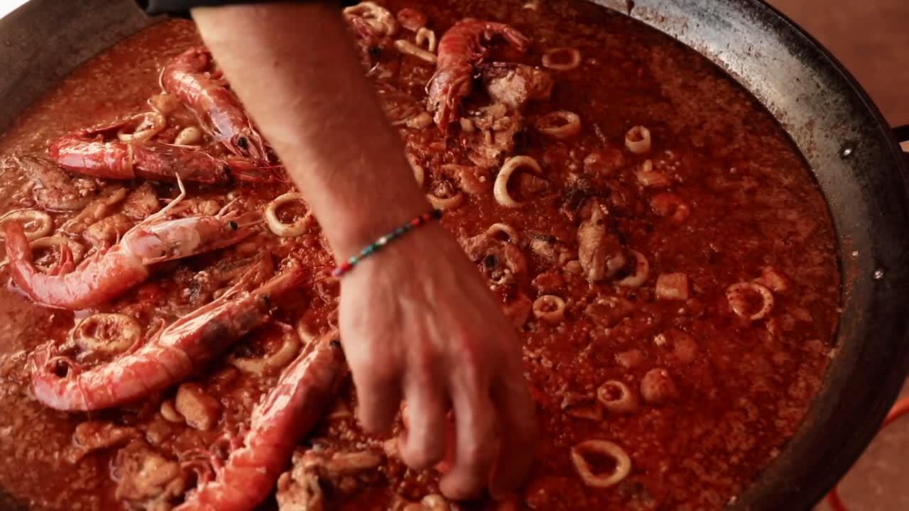 요리사가 새우를 추가하는 동안 빠에야의 궤도 샷