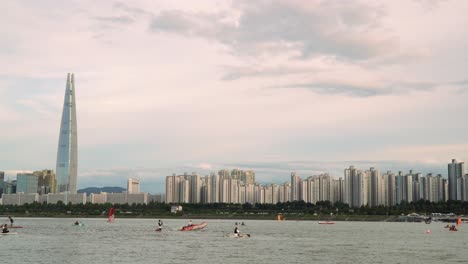 torre de lotte en corea del sur - río han con gente disfrutando del windsurf, paddleboarding, paseos en bote y kayak con el horizonte de seúl en el fondo