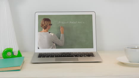 animation of a laptop with caucasian female teacher writing on a blackboard on the screen