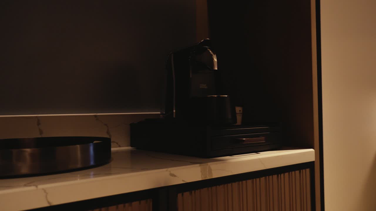 Slider shot revealing a modern hotel room from a coffee station. High-end hospitality interior featuring luxury bedding, designer furniture, and elegant ambient lighting