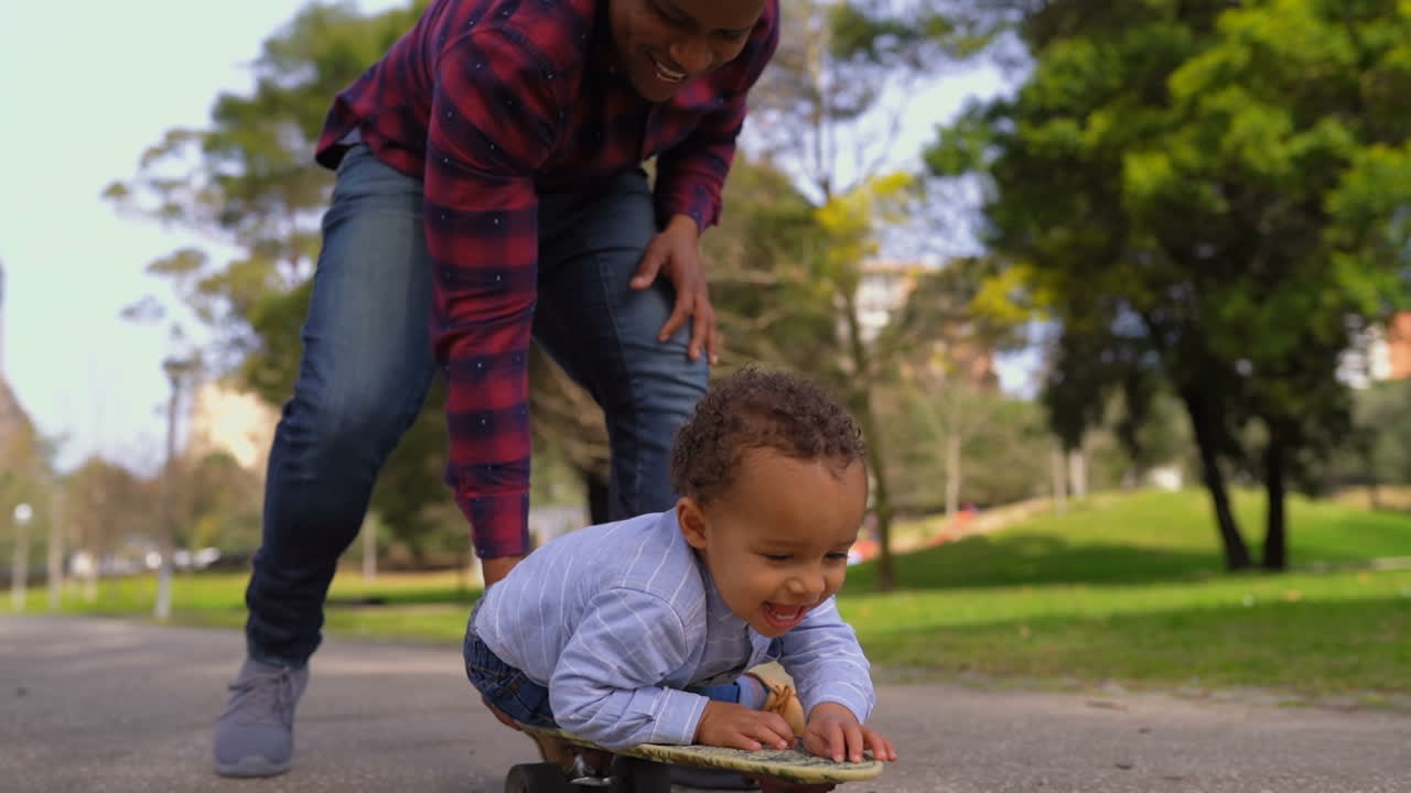 Boy lying on skateboard, rolling to camera with help of father
