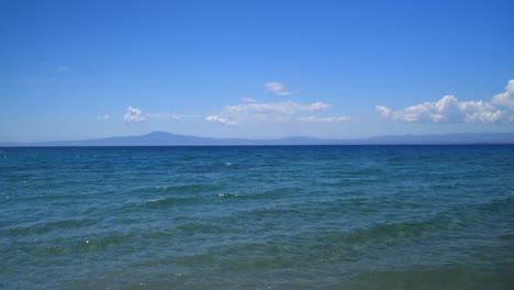 Amplia-Panorámica,-Movimiento-Panorámico-A-La-Derecha,-Sorprendentes-Colores-Azules-En-El-Mar-De-Kalamata,-Peloponeso,-Grecia-Con-Hermosas-Nubes-En-El-Cielo-Azul-4k