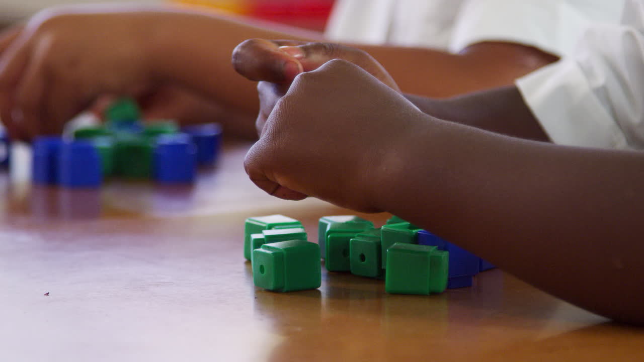Elementary school kids' hands playing with blocks, close up