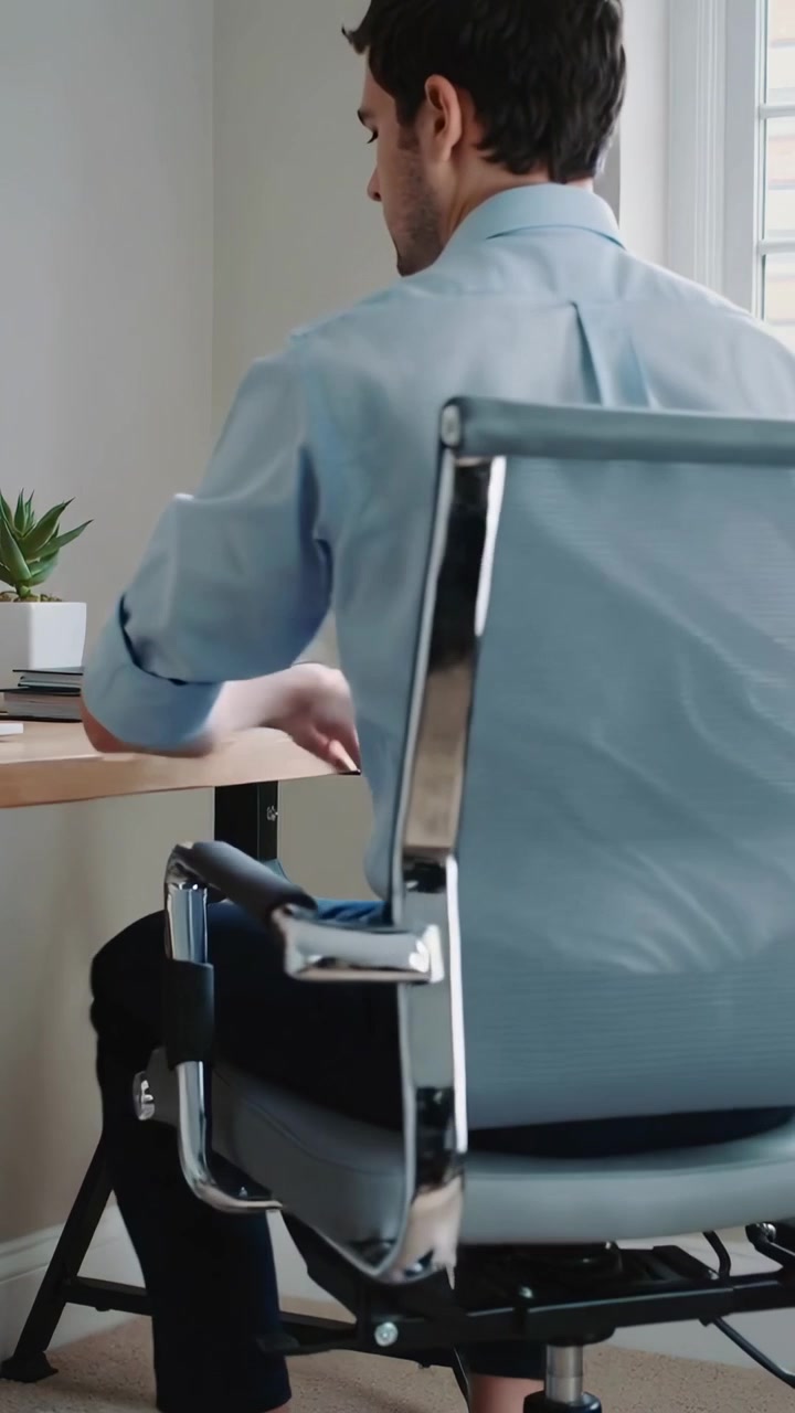 Video verticale: Uomo in camicia blu che si allunga per prendere dei quaderni, girando la sedia alla scrivania dell'ufficio e sistemandosi.