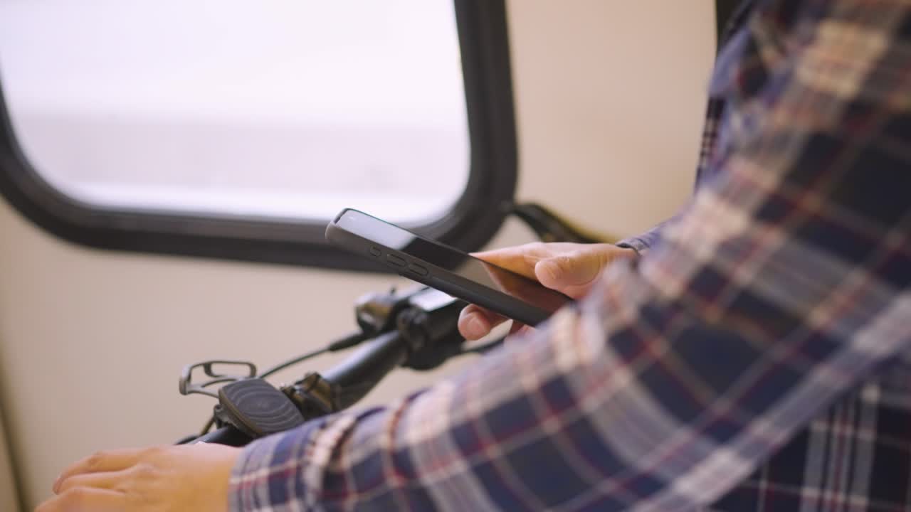 A man is checking his phone while on the train.