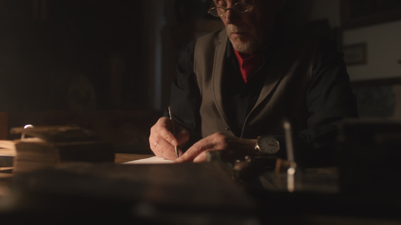 Old passionate man writes a letter in his office at night