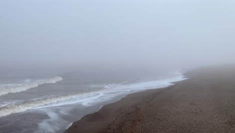 Una-Costa-Brumosa-Con-Olas-Rodando-Hacia-La-Orilla-De-La-Playa-Bajo-Un-Cielo-Gris-Neblinoso