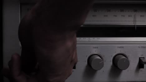 slow motion hand reaching in to turn on power switch for old school am fm wireless radio player